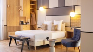 Una habitación de hotel moderna con una cama grande, mesitas de noche, un armario y una zona de estar.