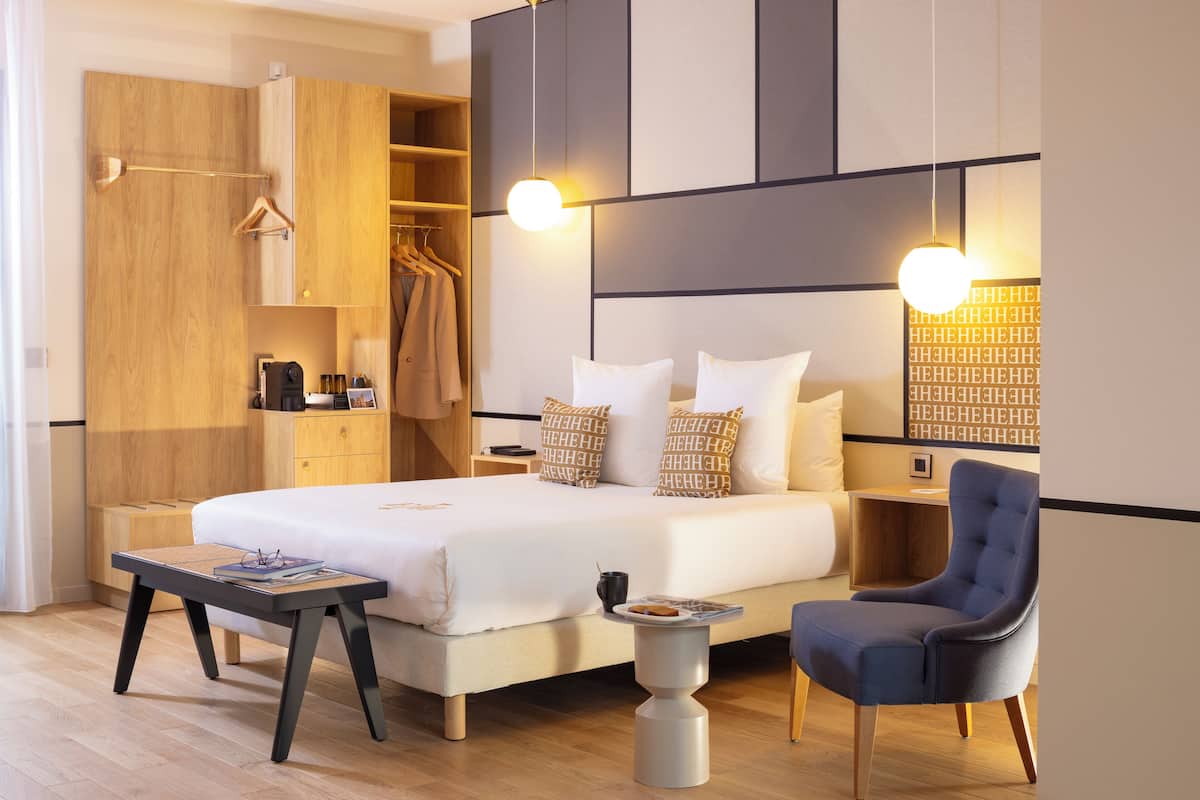 Ein modernes Hotelzimmer mit einem großen Bett, Nachttischen, einem Kleiderschrank und einer Sitzecke.