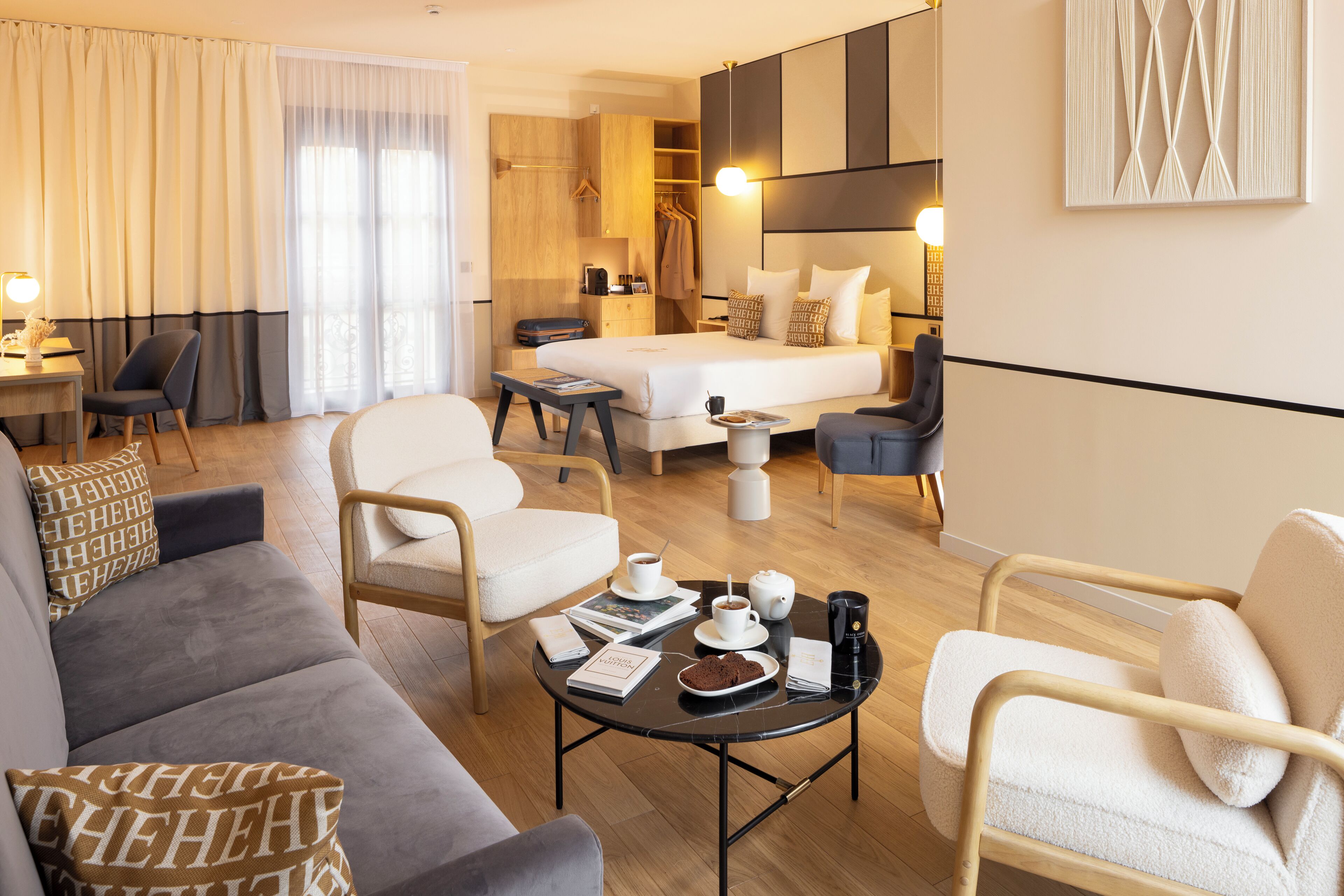 A modern hotel room with a bed, seating area, and a dining table with breakfast items.