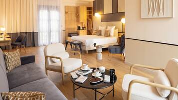 A modern hotel room with a bed, seating area, and a dining table with breakfast items.