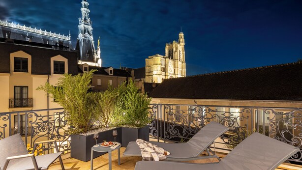 Una terraza en la azotea con sillones de descanso, una mesita y una planta en maceta.