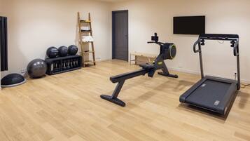 Une salle de sport équipée d’un tapis de course, d’un vélo d’exercice et de divers appareils de musculation.