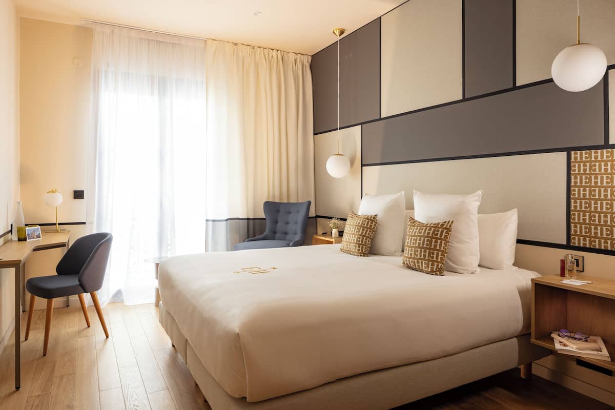 Ein Hotelzimmer mit einem großen Bett, einem Schreibtisch, einem Sessel und einem Nachttisch.