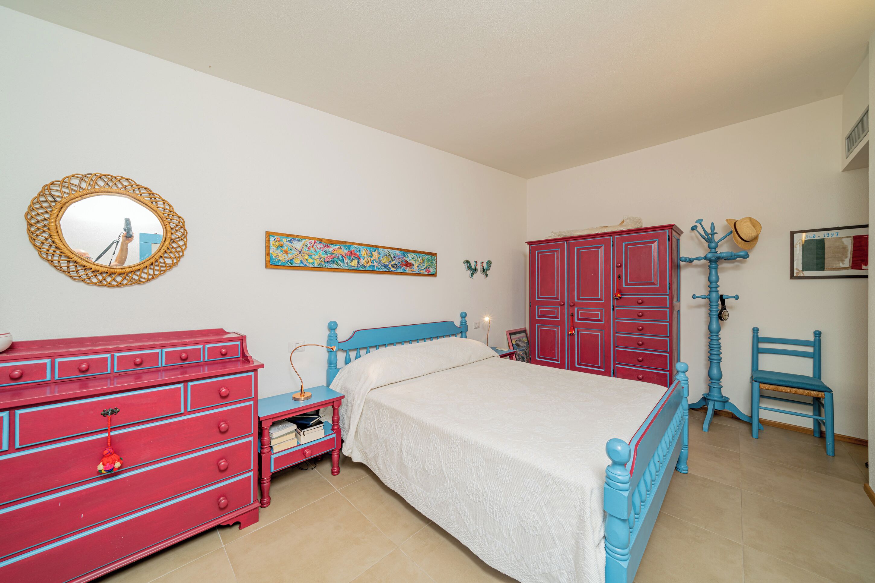 A bedroom with a bed, a dresser, a chair, and a mirror.