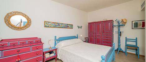A bedroom with a bed, a dresser, a chair, and a mirror.