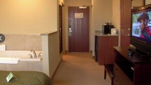 A hotel room with a bed, a television, a bathroom with a sink and mirror, and a door leading to another room. - Werry'S Cottages And Pub By OYO East Stroudsburg - Weekly Stays (East Stroudsburg)
