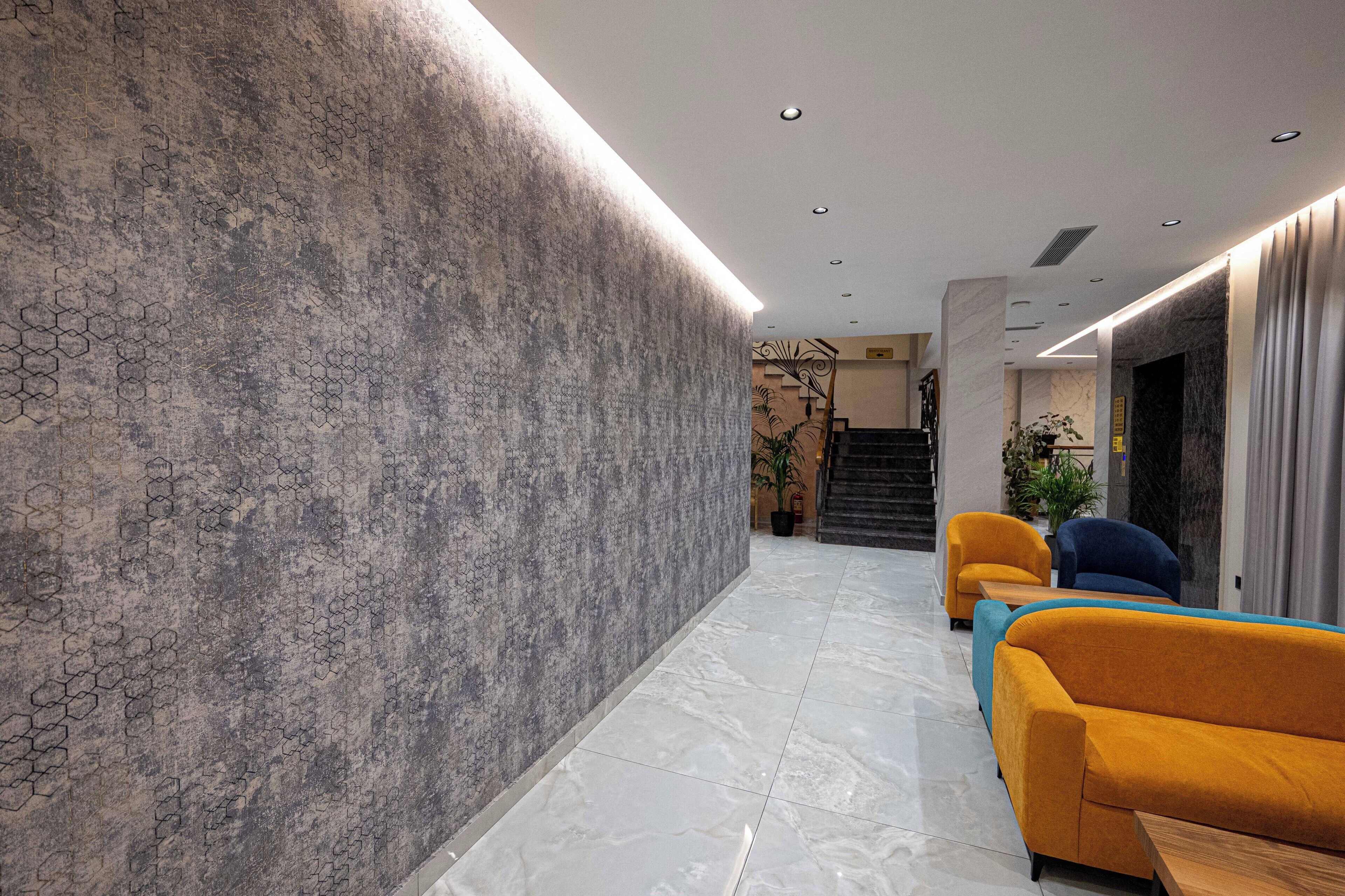 A modern lobby with a textured wall, a marble floor, and two sofas.