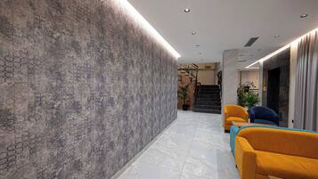 A modern lobby with a textured wall, a marble floor, and two sofas.