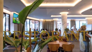 A restaurant interior with tables, chairs, and large windows. - Hotel Dior (Krujë)