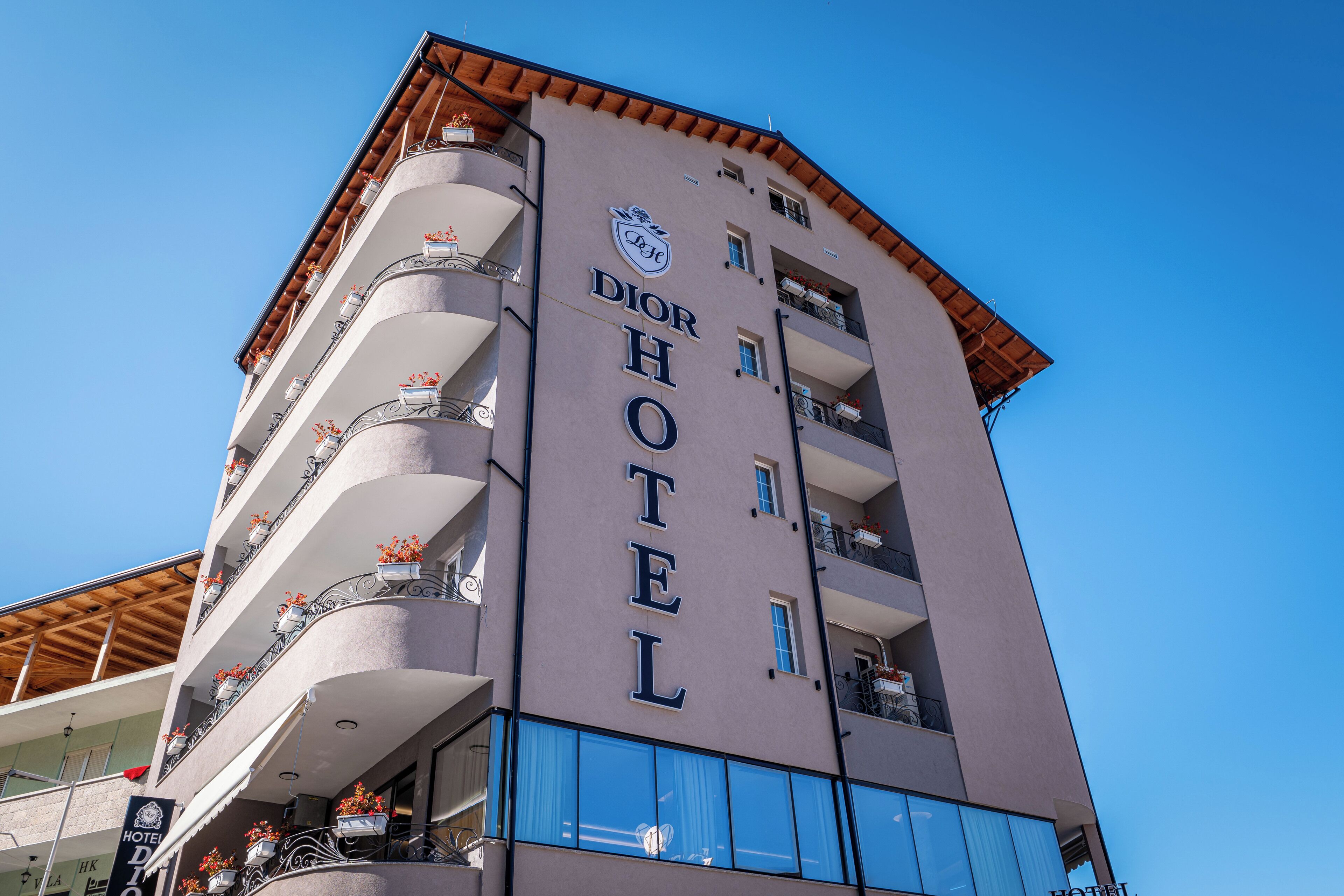 Et hotel med balkoner, et skilt der viser "Dior Hotel", og en klar blå himmel i baggrunden.