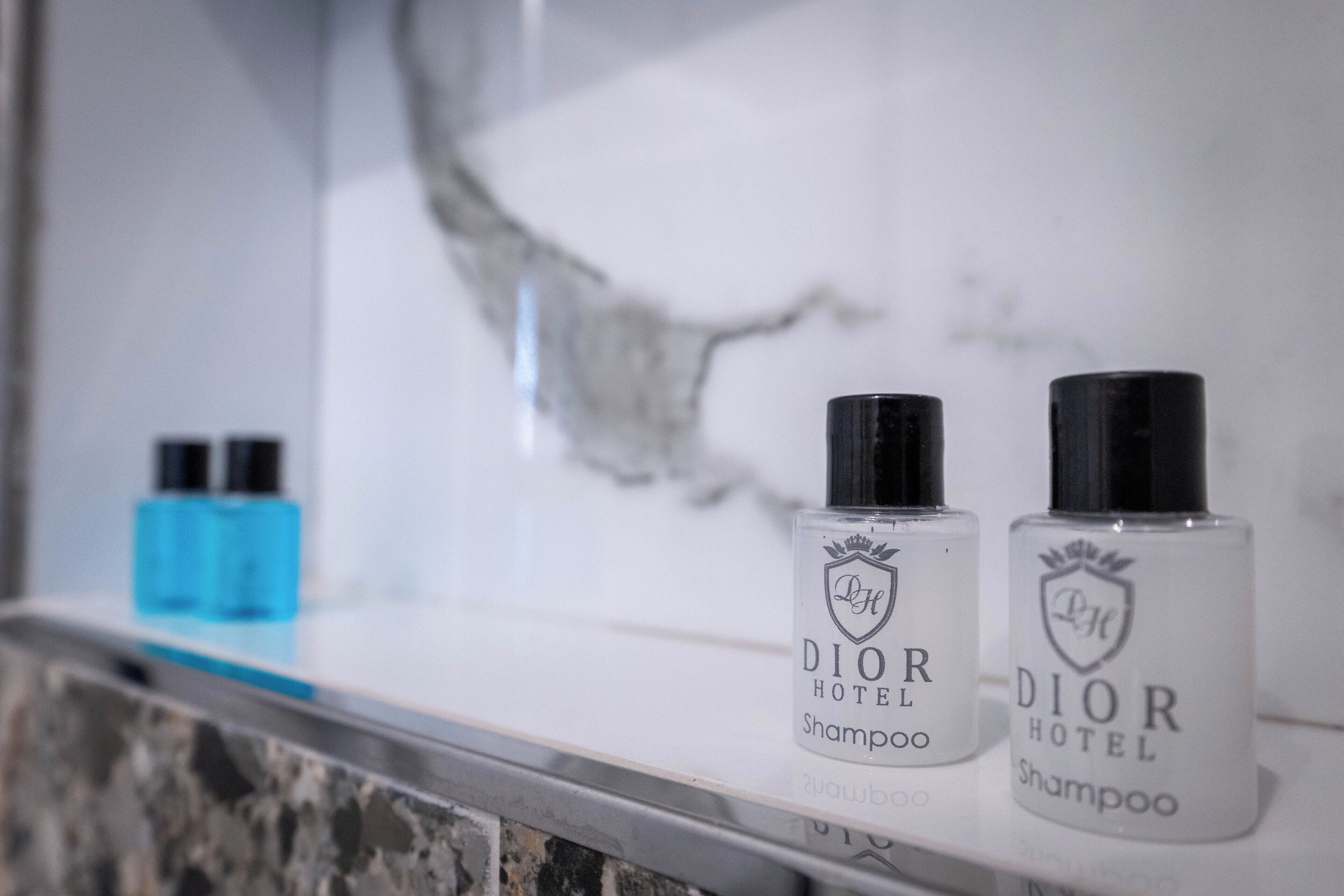 Dos botellas de champú Dior Hotel sobre una repisa de mármol.