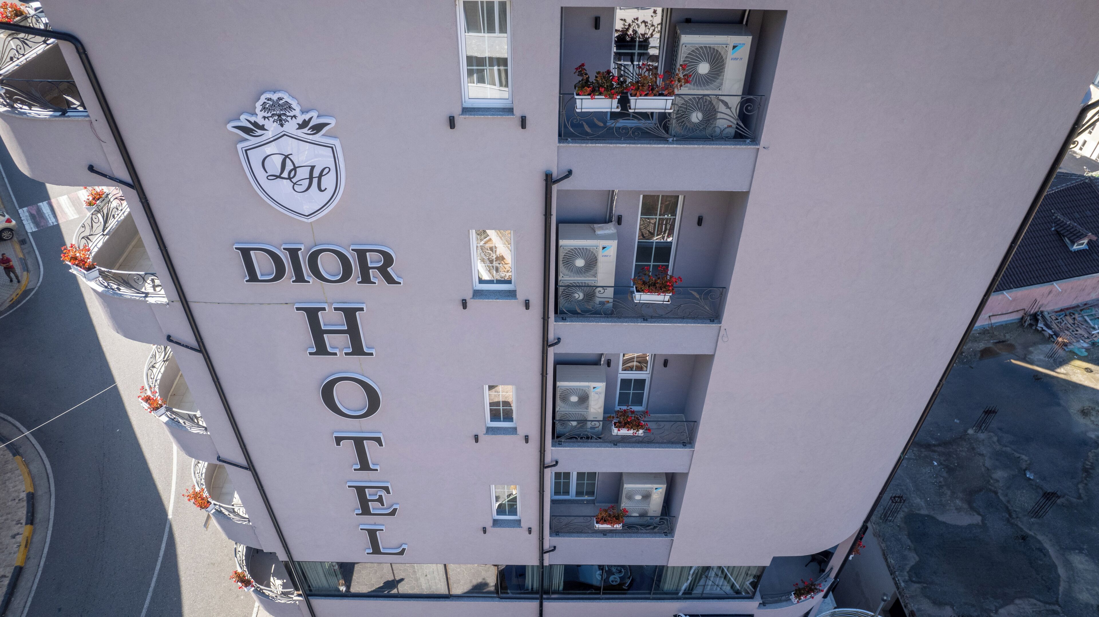 A multi-story building with a sign reading "DIOR HOTEL" and a crest above it.
