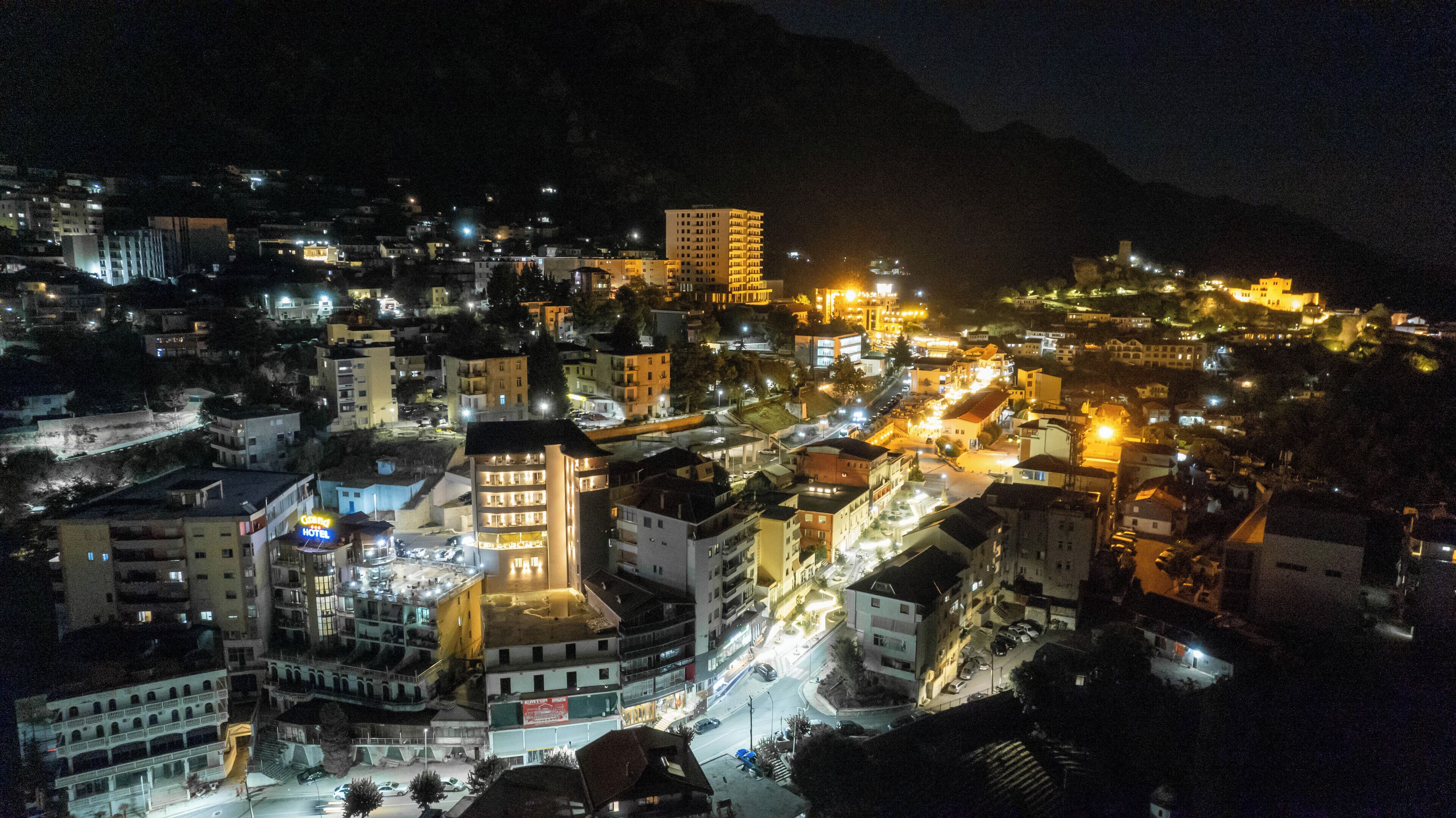 A hotel with multiple floors, a central courtyard, and a view of the surrounding cityscape at night.