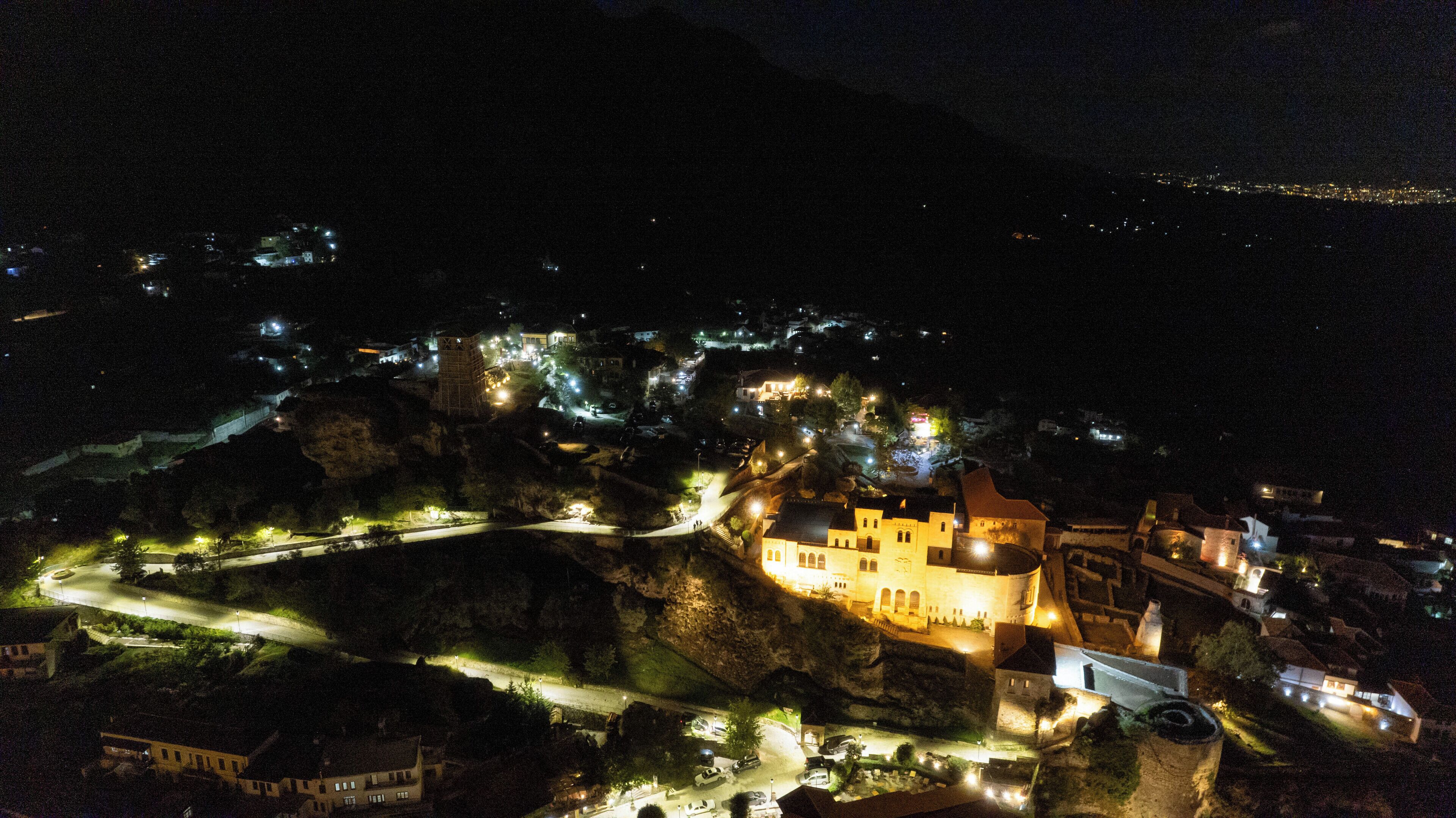 Um edifício histórico com uma torre imponente, localizado numa encosta com edifícios circundantes e uma estrada sinuosa.