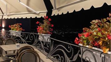 An outdoor dining area with tables and chairs, a railing with decorative elements, and potted plants.