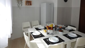 A dining area with a white table set for four, including plates, cutlery, and glasses. - Seacastle Residence Peniche (Atouguia da Baleia)