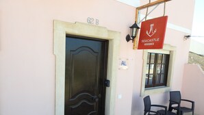 A building entrance with a dark wooden door, a sign reading "Seacastle Residence," and two plastic chairs outside. - Seacastle Residence Peniche (Atouguia da Baleia)