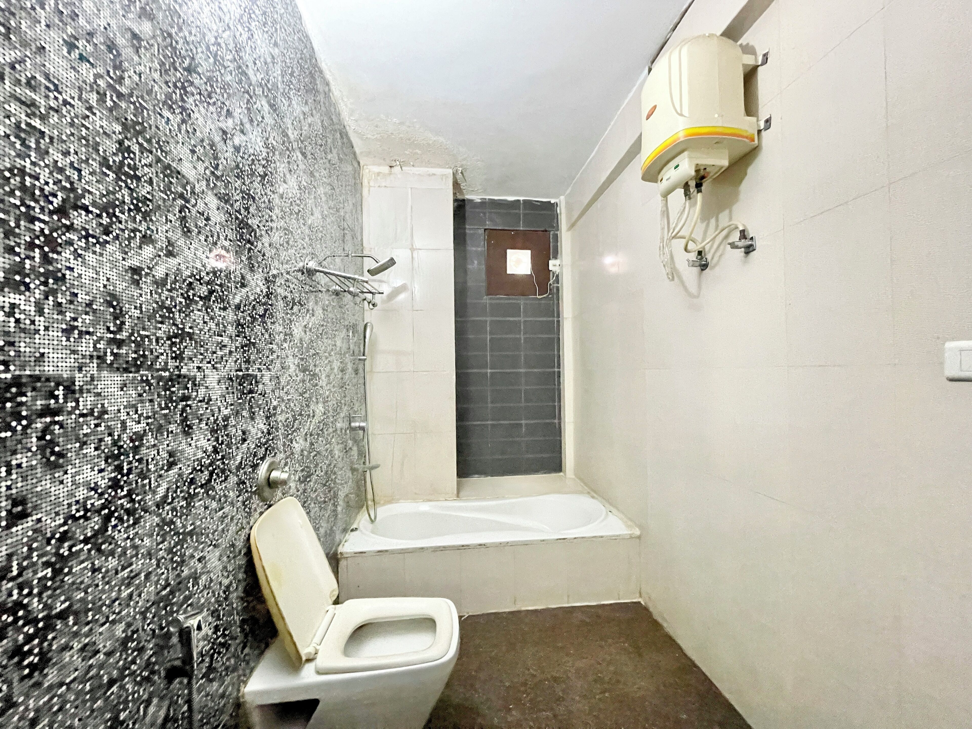 A bathroom with a mosaic wall, a toilet, a shower, and a bathtub.