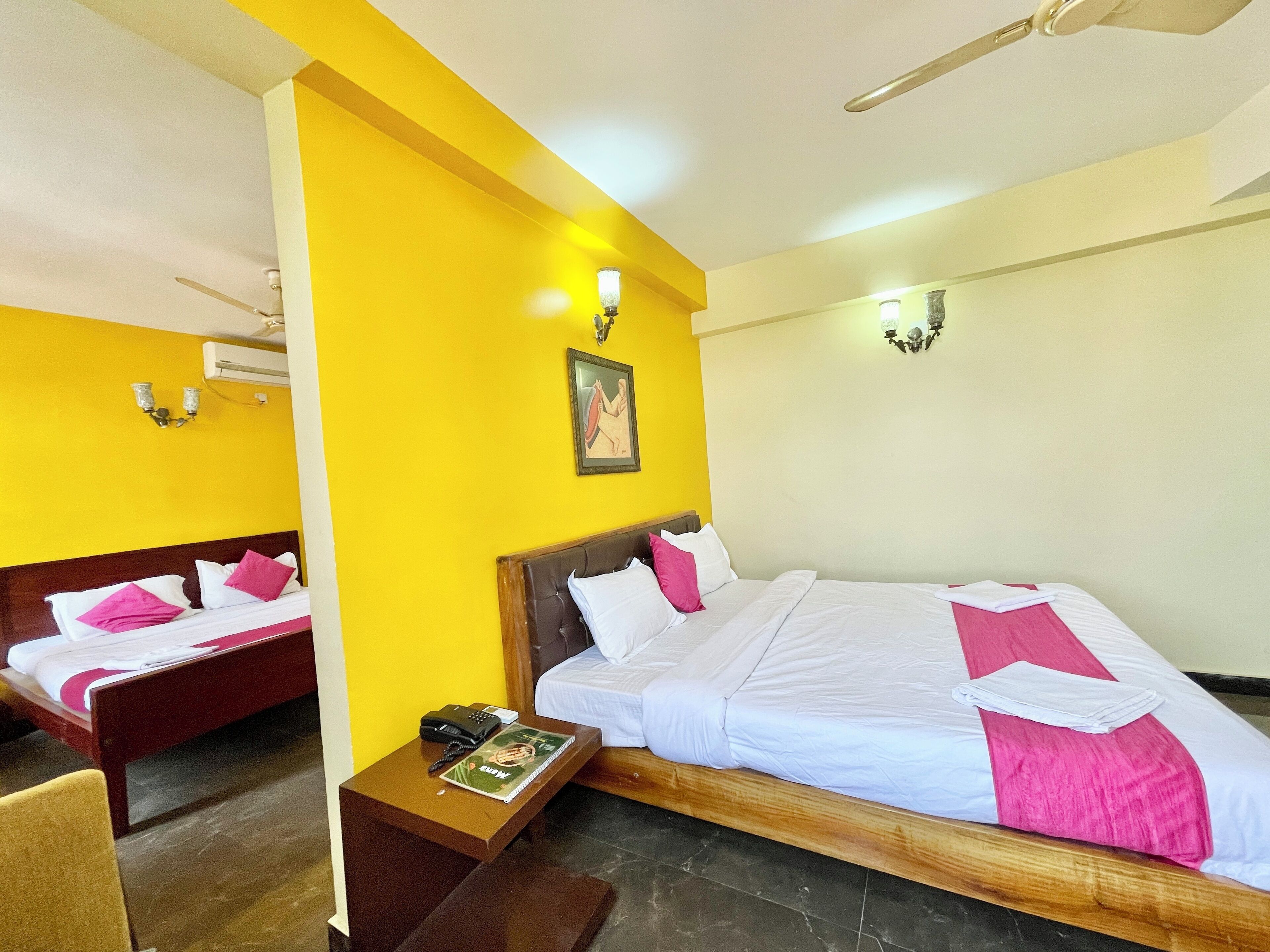 A hotel room with two beds, a small table, a telephone, and a picture on the wall.