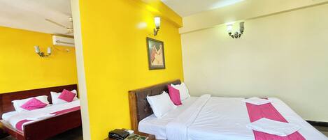 A hotel room with two beds, a small table, a telephone, and a picture on the wall.
