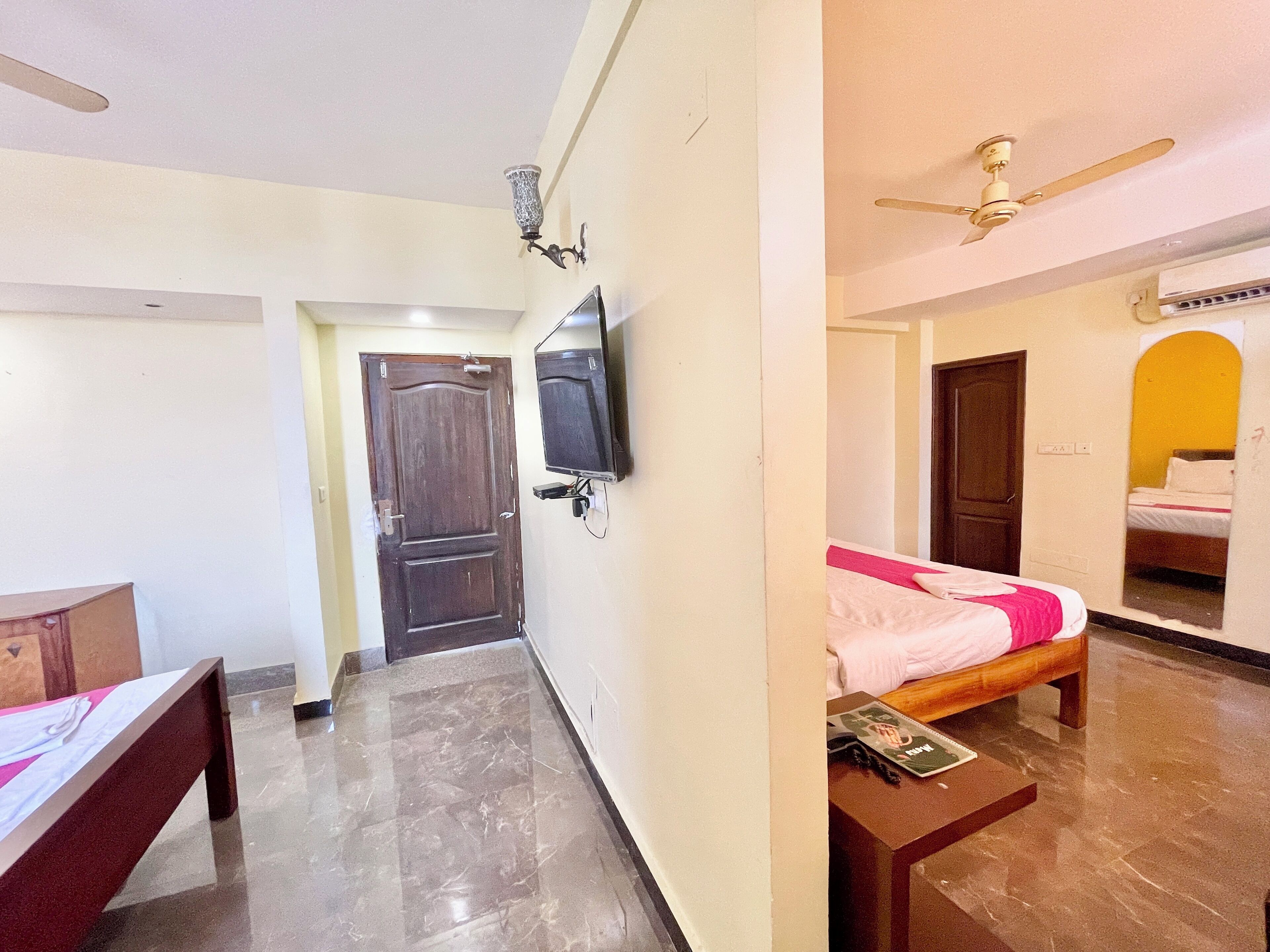 A hotel room with a bed, a desk, a television, and a ceiling fan.