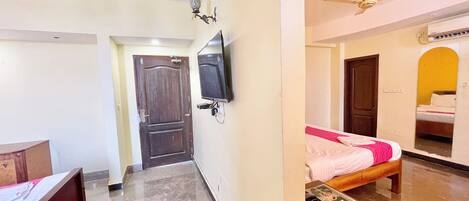 A hotel room with a bed, a desk, a television, and a ceiling fan.