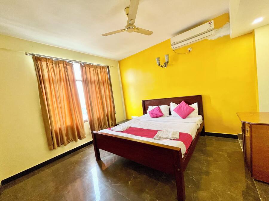 Habitación de hotel con cama, cortinas, ventilador de techo y aire acondicionado.