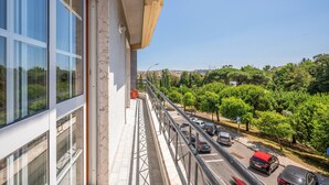 Un balcon donnant sur une route et sur un espace verdoyant.