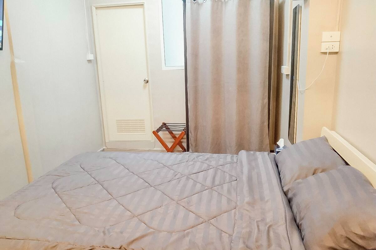 A bedroom with a bed, curtains, a chair, and a door.