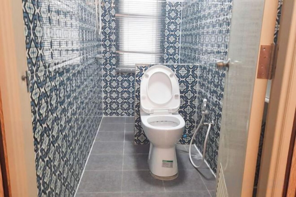 A bathroom with a toilet, a shower, and a tiled wall.