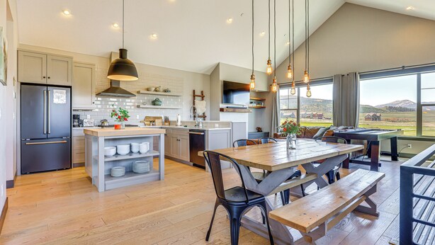 A modern kitchen with a central island, wooden flooring, and pendant lighting. - Hot Tub & Mtn Views: Townhome in Granby! (Granby)