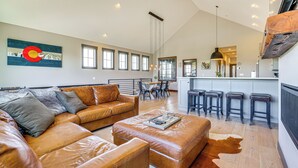 A spacious living room with leather sofas, a coffee table, and a large window. - Hot Tub & Mtn Views: Townhome in Granby! (Granby)