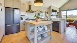 A modern kitchen with a central island, stainless steel appliances, and a large window offering a view of the outdoors. - Hot Tub & Mtn Views: Townhome in Granby! (Granby)