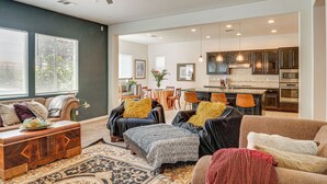 A spacious living room with a sofa, ottoman, and coffee table, a dining area with chairs, and a kitchen with cabinets and appliances. - Rio Bravo Country Club Home in Bakersfield w/ Pool (Bakersfield)