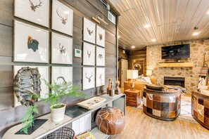A cozy living room with a stone fireplace, a mounted TV, and a wall adorned with framed animal heads.