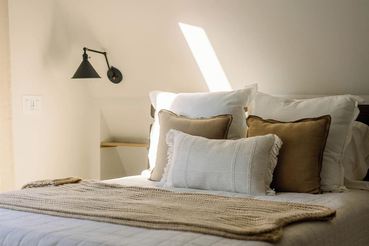 A neatly made bed with a quilted bedspread, a throw blanket, and several pillows.