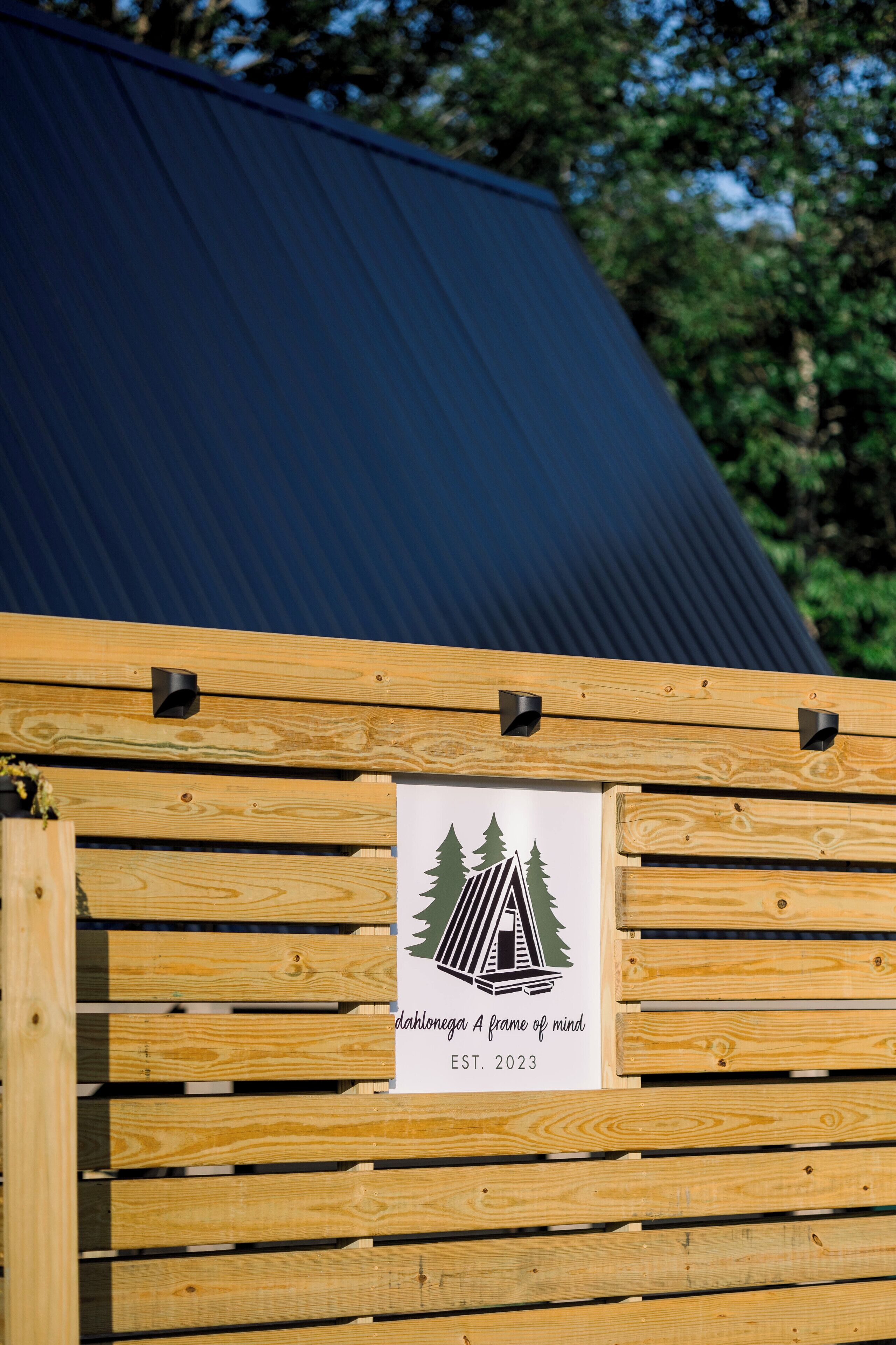 Una estructura de madera con un letrero que indica 'dahlenegga A frame of mind EST. 2023'.
