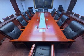 A conference room with a long table, black chairs, and a projector screen. - Suining Linhai Hotel (Suining)