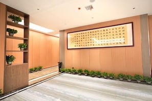 A hallway with a wooden floor, potted plants, and a large framed text on the wall. - Suining Linhai Hotel (Suining)