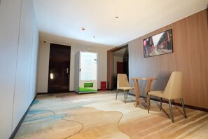 A hotel room with a wooden wall, a painting, a desk, and a chair. - Suining Linhai Hotel (Suining)