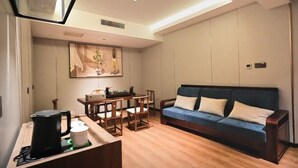 A modern living room with a sofa, a coffee table, and a dining area. - Suining Linhai Hotel (Suining)