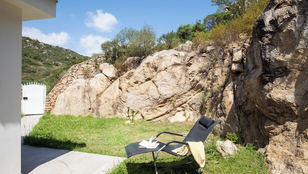 Una poltrona da relax con un libro e un asciugamano, una parete in pietra e una zona verde.