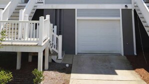 Un immeuble résidentiel à deux étages, doté d’un garage à l’avant, d’un porche couvert et d’un escalier menant à l’entrée.