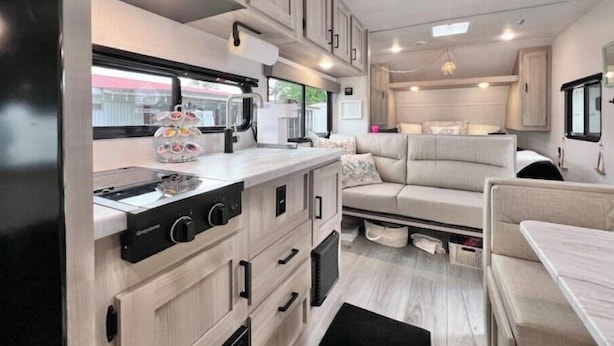 A compact RV kitchen with a stove, microwave, and a small dining area.