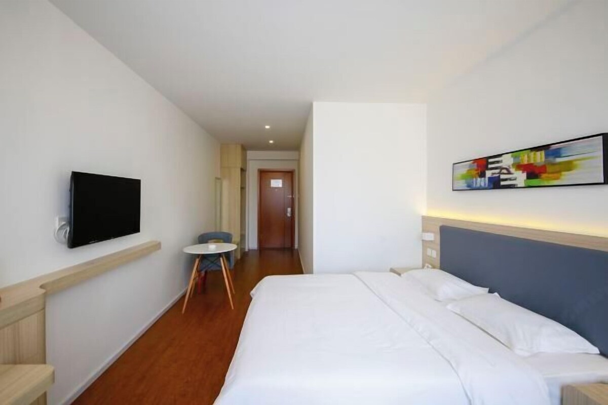 Ein Hotelzimmer mit Bett, Fernseher, kleinem Tisch und Stuhl.