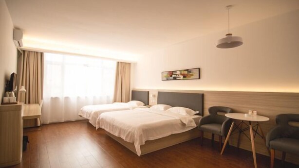 A hotel room with two beds, a desk, a chair, a small table, and a window with curtains. - Super 8 Inn Jilin Shenzhen Street (Jilin City)