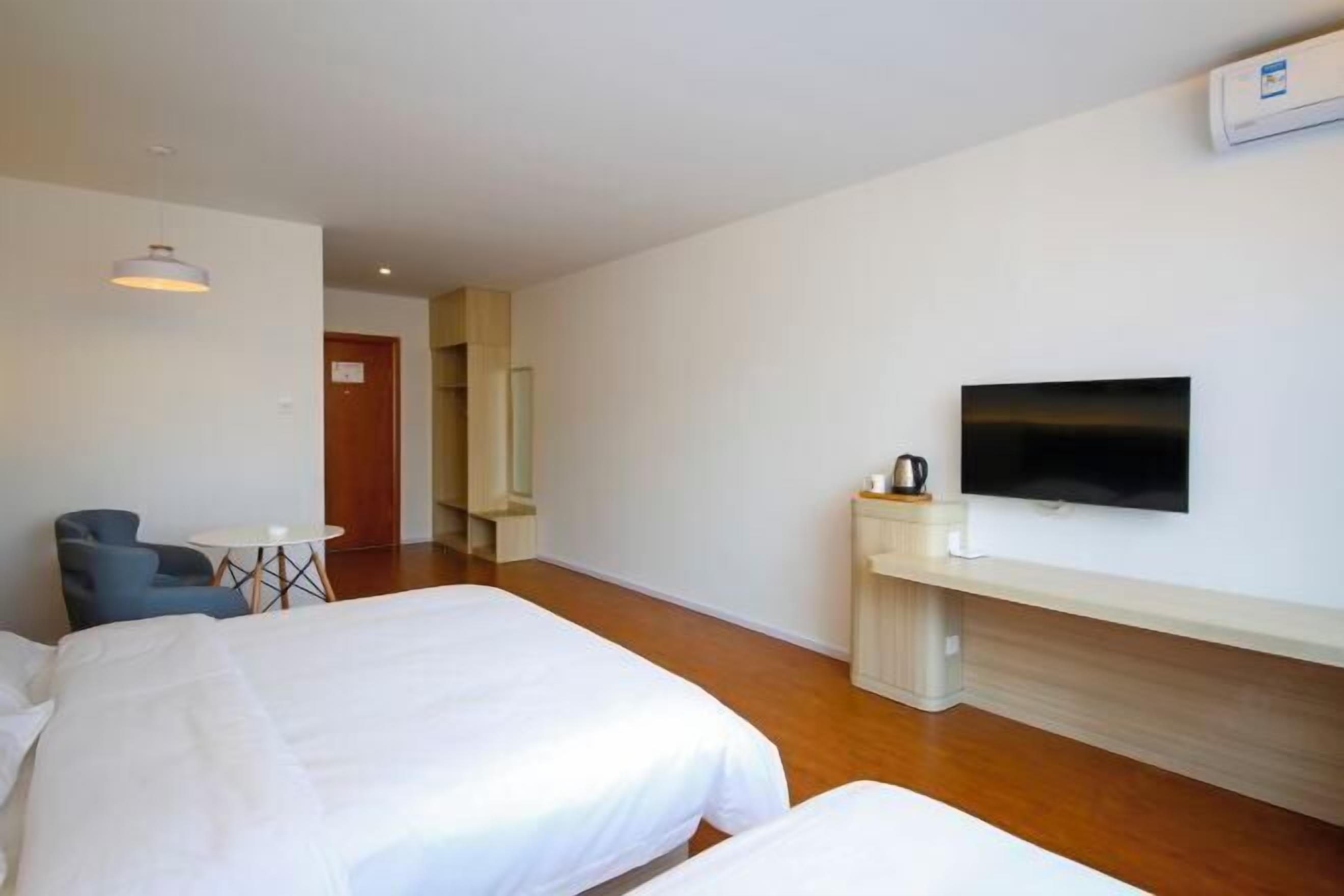 Una habitación de hotel con dos camas, un televisor, una mesita y una silla.