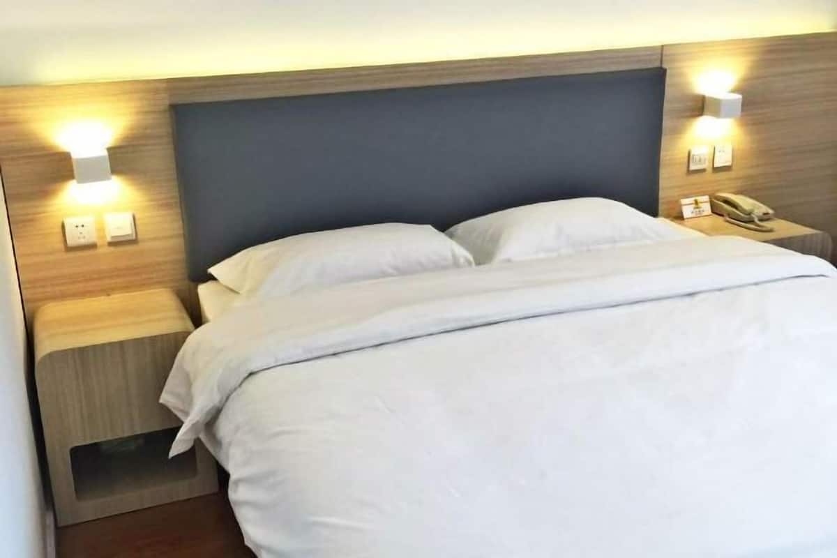 A neatly made bed with white linens, a wooden headboard, and bedside lamps.