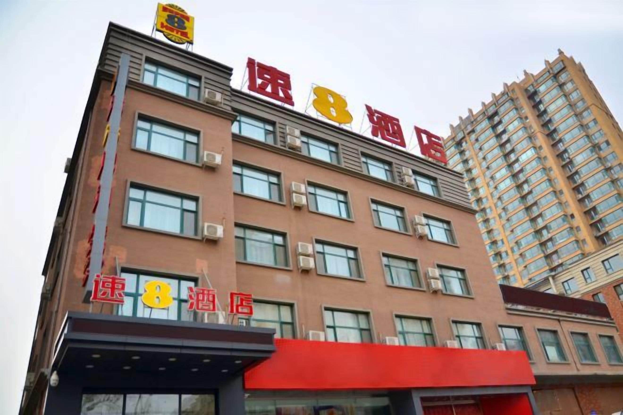 A hotel building with multiple floors and a prominent red sign indicating its name.
