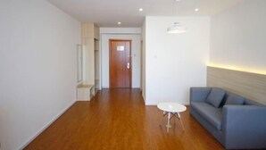 A modern living room with a wooden floor, a blue sofa, a small white table, and recessed ceiling lighting. - Super 8 Inn Jilin Shenzhen Street (Jilin City)